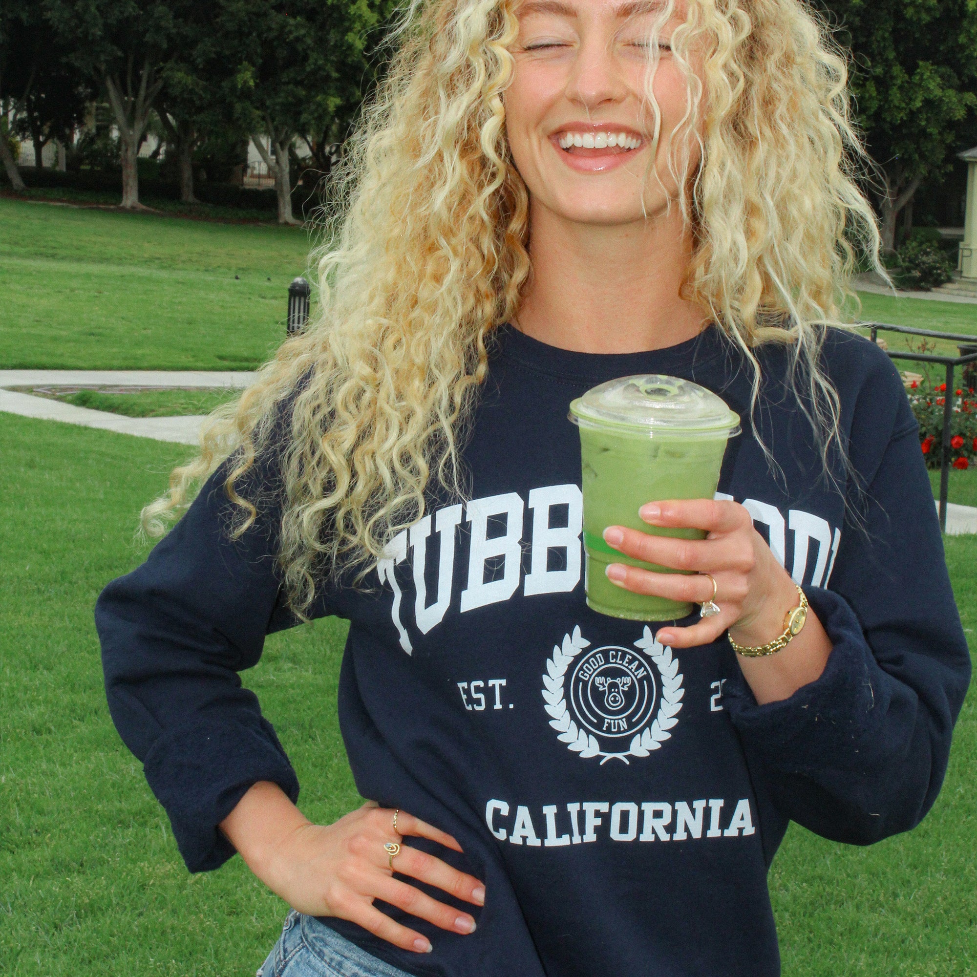 Women wearing the new TT Sweatshirt and smiling at the park.